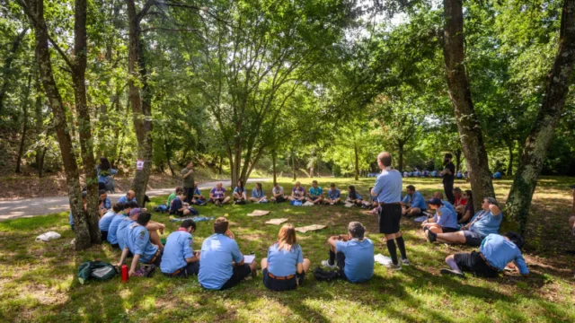 giovani persone scout sedute a terra in cerchio in un bosco