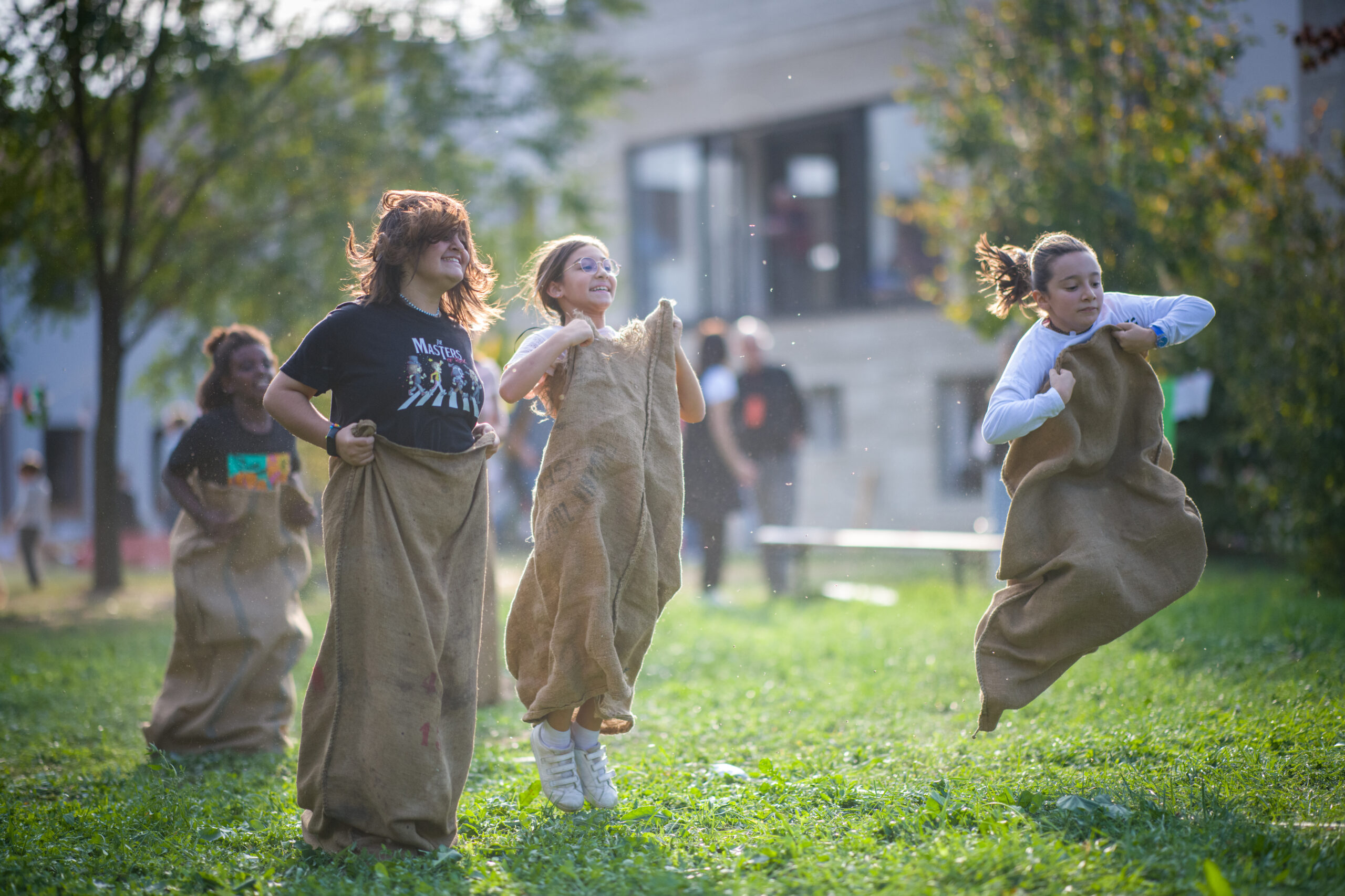 4 bambine che saltano nei sacchi su un prato