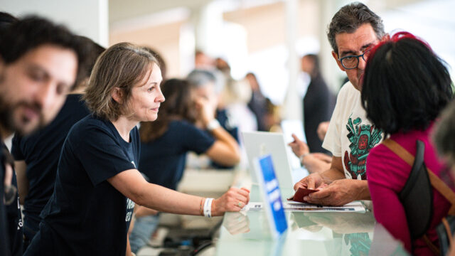 Soci durante l’assemblea dei soci a Valencia mentre conversano e si registrano al banco accoglienza.