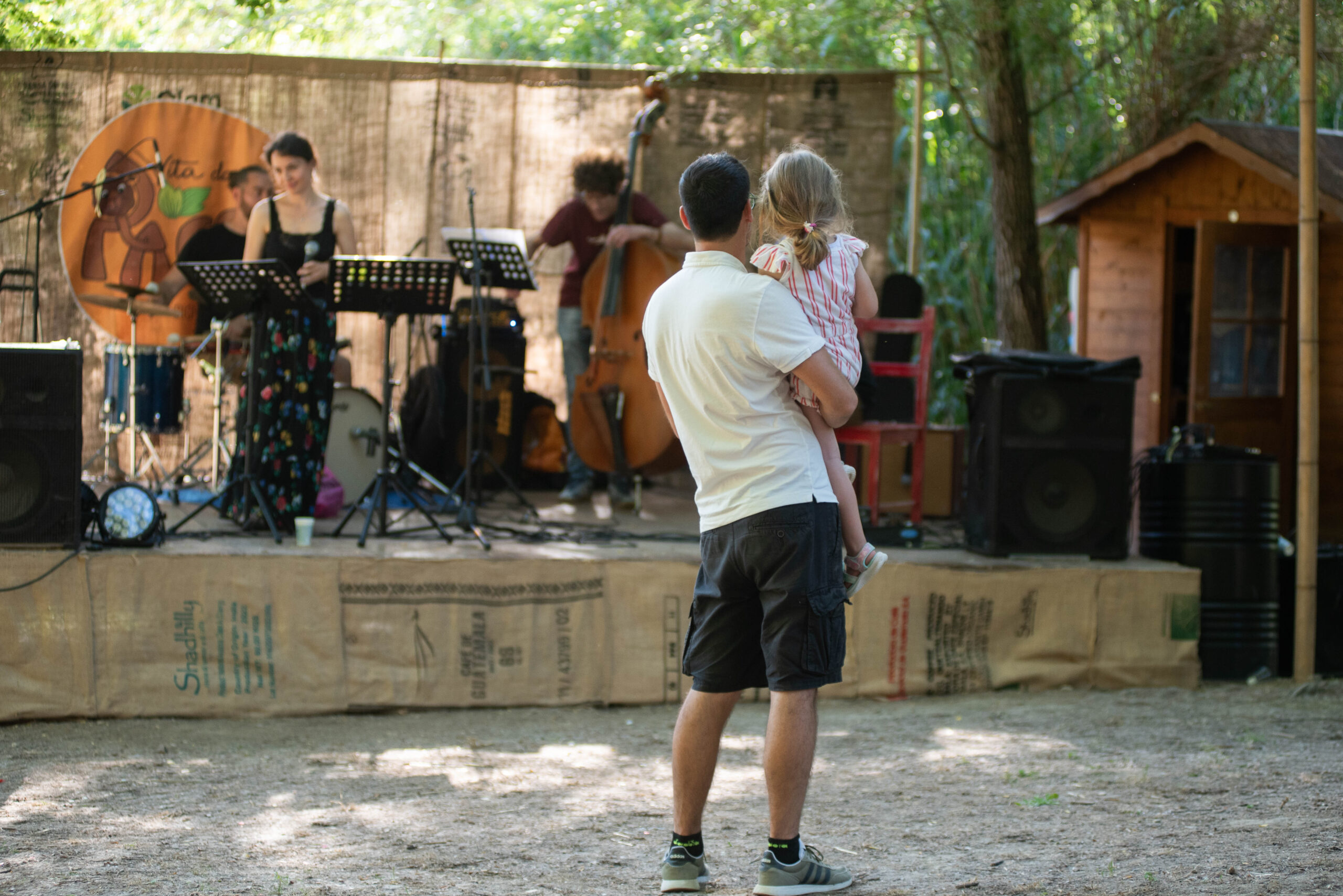 Padre con una bambina in braccio che ascoltano un concerto all’aperto in un bioparco.
