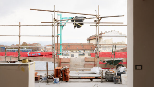 Cantiere edile in corso: impalcatura, materiali da costruzione e, sullo sfondo, i tetti di un quartiere urbano