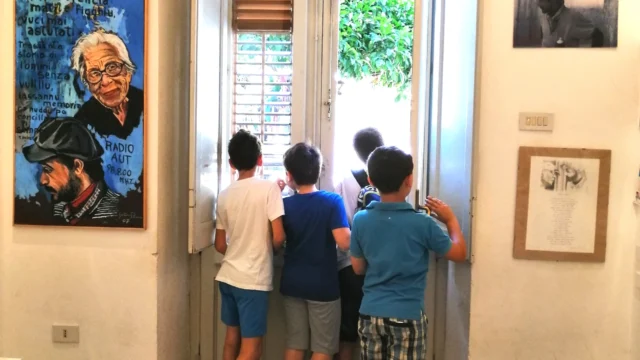 Bambini all’interno di Casa Memoria Impastato guardano fuori dalla finestra.