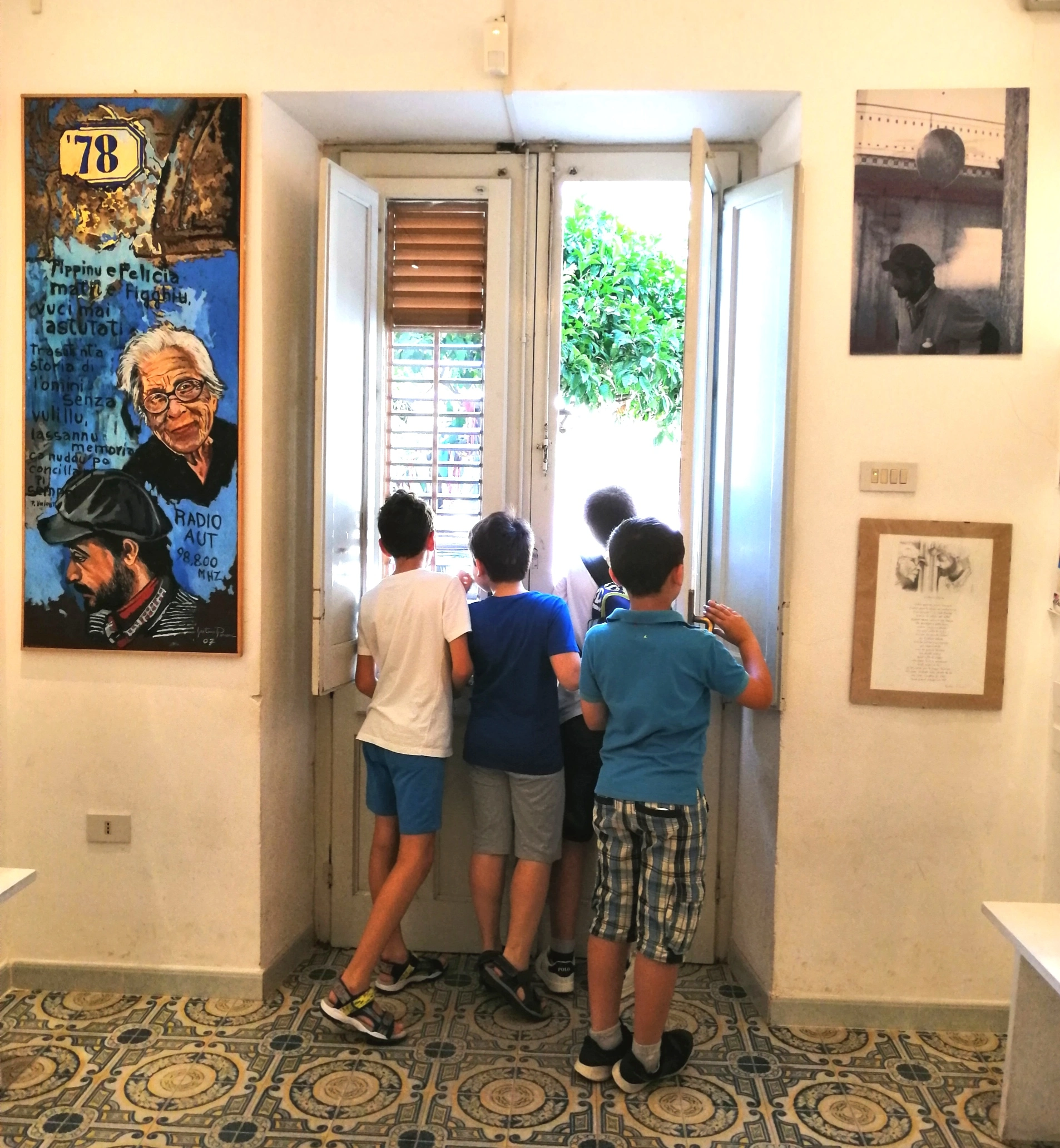 Bambini all’interno di Casa Memoria Impastato guardano fuori dalla finestra.