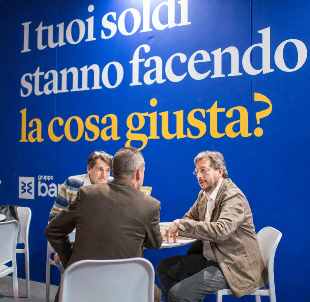 Tre persone sono sedute ad un tavolo e si confrontano sui prodotti e servizi di Banca Etica